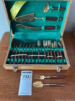 Full open case of mid-century bronze flatware with rosewood handles, showing entire service for 8 plus serving pieces inside turquoise lined wooden box.