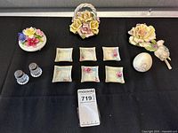 Full view of all porcelain flower décor items, salt dishes, egg, and glass salt and pepper shakers arranged on black background.