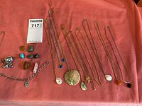 Overview photo showing the entire lot with necklaces, loose pendants, and a charm bracelet arranged on a pink background.