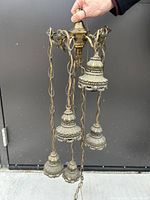 Photo of three vintage brass hanging lamp chains with decorative end fixtures and patina.