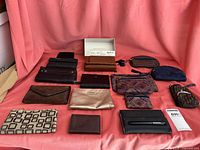 View of entire lot with 11 items including wallets, purses, and gloves arranged on pink cloth.