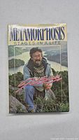 Front cover of the book "Metamorphosis: Stages in a Life" showing author David Suzuki sitting outdoors with scenic background.