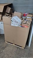 Front view of large Gaylord box on pallet filled with cardboard boxes and loose books