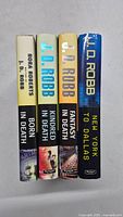 Four hardcover books by J.D. Robb, showing spines with titles and author names.