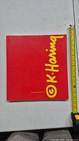 Front cover of the red Keith Haring book with large yellow signature style text and tape measure.
