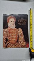 Front cover of the large hardcover art book titled 'The National Portrait Gallery Collection' showing a detailed historical portrait and a measuring tape alongside it showing roughly 12 inches in height.