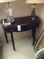 Front-angle photo showing the curved top, fluted legs, and expansion mechanism of the antique table with some decorative items placed on it.