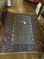 Full view of rectangular area rug with geometric floral pattern showing overall condition and size on hardwood floor.