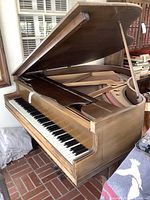 Side and front angle showing the open lid revealing keyboard and external wooden body with worn patina.