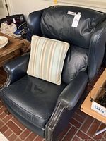 Front angle view of navy leather recliner with striped throw pillow on seat