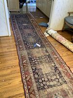 Full length photo of the long area rug placed on hardwood floor showing overall wear and pattern.