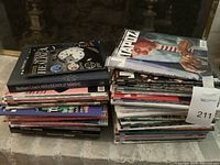 Two stacks of assorted magazines placed on a stone surface in front of a fireplace.