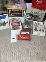 Full lot overview showing multiple light-up Christmas village pieces including McDonald's and Coca-Cola branded items with original packaging.