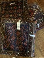 Three cushions made from Persian rugs showing traditional geometric and floral patterns in red, blue, and cream colors. The cushions measure 23x23 inches each.