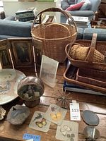 Overview of various items on table including baskets, pottery plates, geodes, decorative snow globe, and other items.