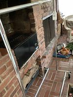 Metal rolling wardrobe rack standing on brick floor near a brick fireplace. Shows overall frame and horizontal bars.
