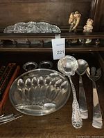 Overall lot of silverware displayed on wood surface with chopsticks, cut glass dish and figurines