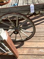 Close-up of aged wooden spoked wheel of wagon showing wear and rustic condition.