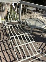 Wrought iron lounge chair and patio table with weathered white finish, showing the overall condition and size of both items on an outdoor deck.