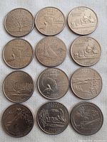 12 USA state quarters arranged in a grid on a white fabric background. Shows detailed state imagery and dates from 2001 to 2013.