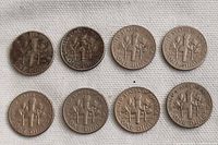 Eight United States dimes reverse side showing torch, olive branch, and oak branch designs.