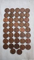 Overview of 40 USA Lincoln pennies arranged in rows on white fabric background showing the obverse side with Abraham Lincoln profile.