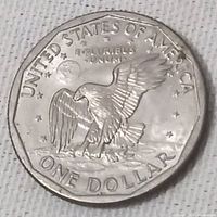Reverse side of 1979 USA one dollar coin showing eagle landing on the moon, with inscriptions around the edge.