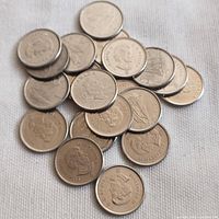 20 Canadian 10 cent coins scattered on white fabric surface showing Queen Elizabeth II obverse and Bluenose schooner reverse sides