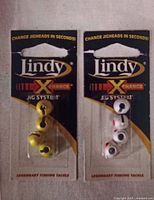 Front view of two Lindy X Change Jig Heads in blister packaging, yellow and white colors visible.