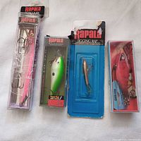Four Rapala brand fishing lures in original packaging displayed on a white surface