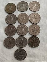 Thirteen US quarters reverse side showing an eagle design and 'United States of America', 'E Pluribus Unum', 'Quarter Dollar'. Coins show varying wear and oxidation.