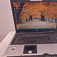 Acer Aspire 9300 laptop powered on showing a fall-themed desktop wallpaper with a path lined by trees.