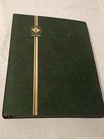 Green Uni-Safe branded stamp album with gold vertical line and emblem on front cover, closed