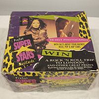 Photo of a 1991 Pro Set Super Stars Music Cards factory box featuring colorful leopard print design, images of music celebrities, and promotional text about 10 hot photocards with facts about rock, pop and rap stars, including a contest to win a trip to London.