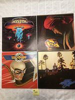 Four vinyl LP album covers: Boston, ELO Discovery, Trooper Flying Colors, and The Eagles Greatest Hits laid out on a white surface.