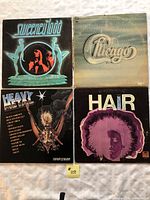 Four vinyl records with covers: Sweeney Todd, Chicago, Heavy Metal double album, Hair soundtrack; arranged on a white cloth background.