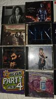 Photo showing 8 CDs from the lot including Michael Jackson Anniversary, Styx Greatest Hits, Andria Bocelli Sogno, BigFun Party Mix 4, and Tilli album.