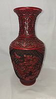 Full view of the cinnabar vase showing overall shape, intricate carvings, and red lacquer.