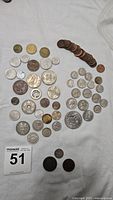 Full array of coins on white cloth showing assortment of various sizes, colors, and ages.