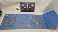 Wide shot of blue coin album with threepence brass coins arranged on three panels, and an additional coin set in a separate display.