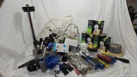 Overview of lot with blue vise, power strips, light bulb boxes, hand tools and accessories.