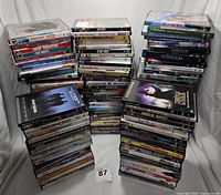 Shows stacks of assorted DVD movies and TV series totaling approximately 130 discs in standard DVD cases.