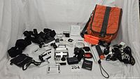 Full lot layout showing GoPro HERO4 camera, batteries, accessories, mounts, chargers, cables, and orange carrying case.