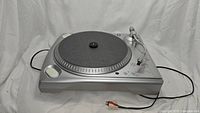 Full view of silver Ion TTUSB turntable showing platter, control buttons, and cables.