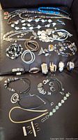 Photo showing the full assortment of costume jewelry laid out including necklaces, bracelets, rings, and earrings on a black surface.