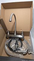 Kinfaucets brushed nickel kitchen faucet set including faucet with high arc spout, side sprayer, and hoses inside original cardboard box.