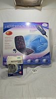 Boxed 6 motor heated massage cushion with image of product and features. Includes remote control and adapters mentioned on box. Also shows Accu-Chek Aviva blood glucose meter box.