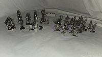 Group photo of pewter figurines including a mix of Star Wars and Disney Monopoly game pieces on a white background