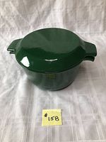 Top and side view of green enameled cast iron casserole with lid on a white background showing its size and shape.