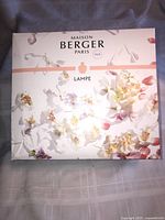 Front of the Lampe Berger Paris box showing floral artwork and branding indicating the product is a fragrance diffuser lamp.